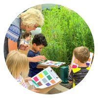 Female adult outside showing young children colors on a piece of paper