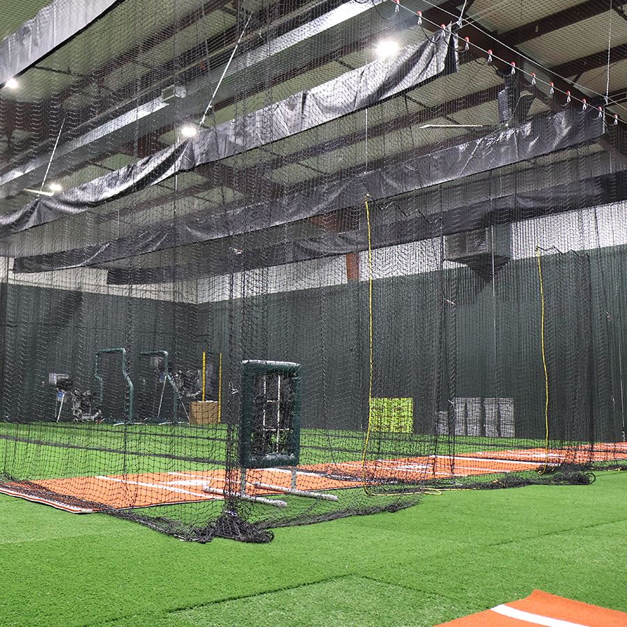 Wide angle shot of Douglass Batting Cages with netting and green turf